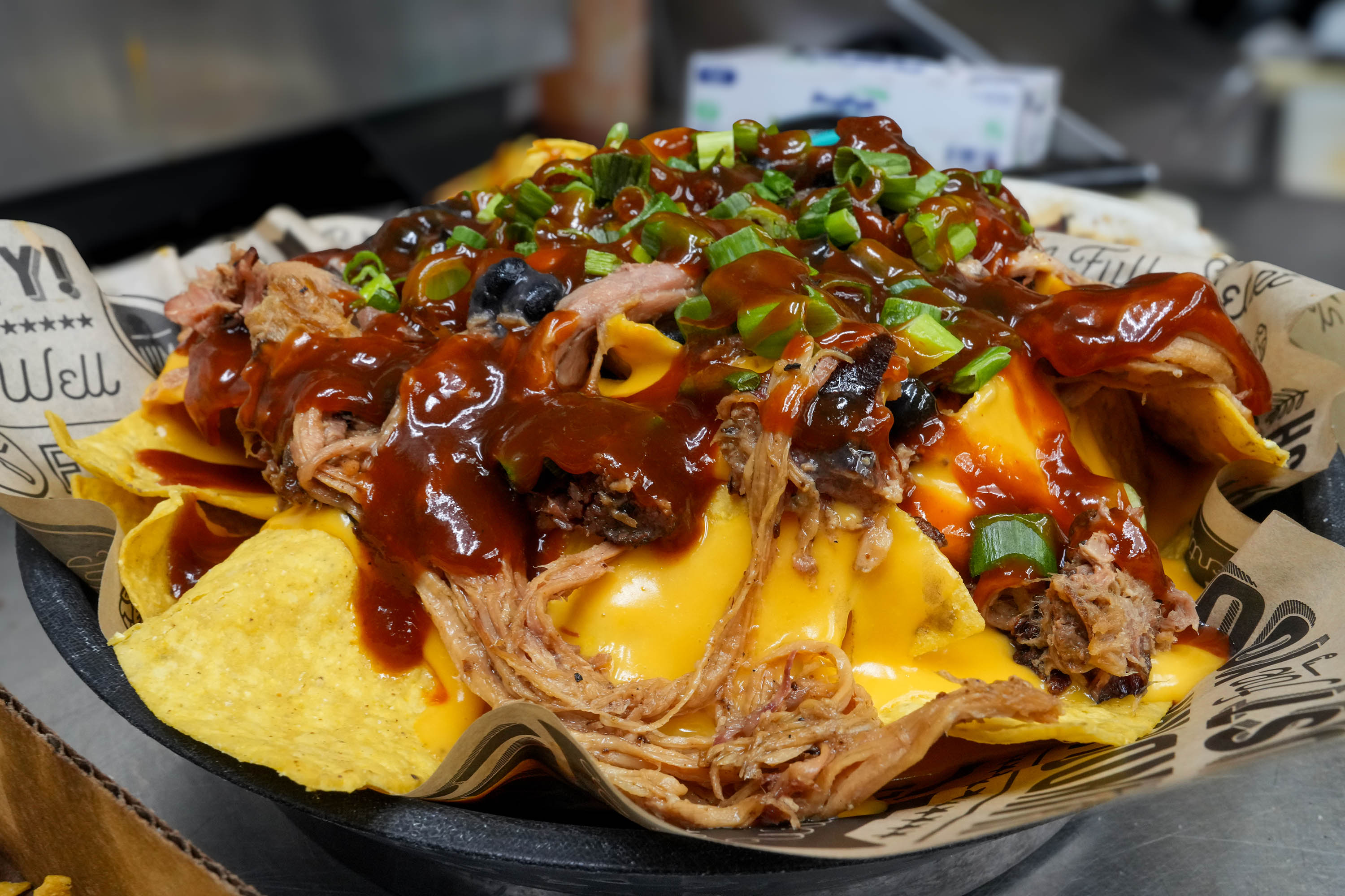 Pulled pork nachos with queso, barbecue sauce, and green onion