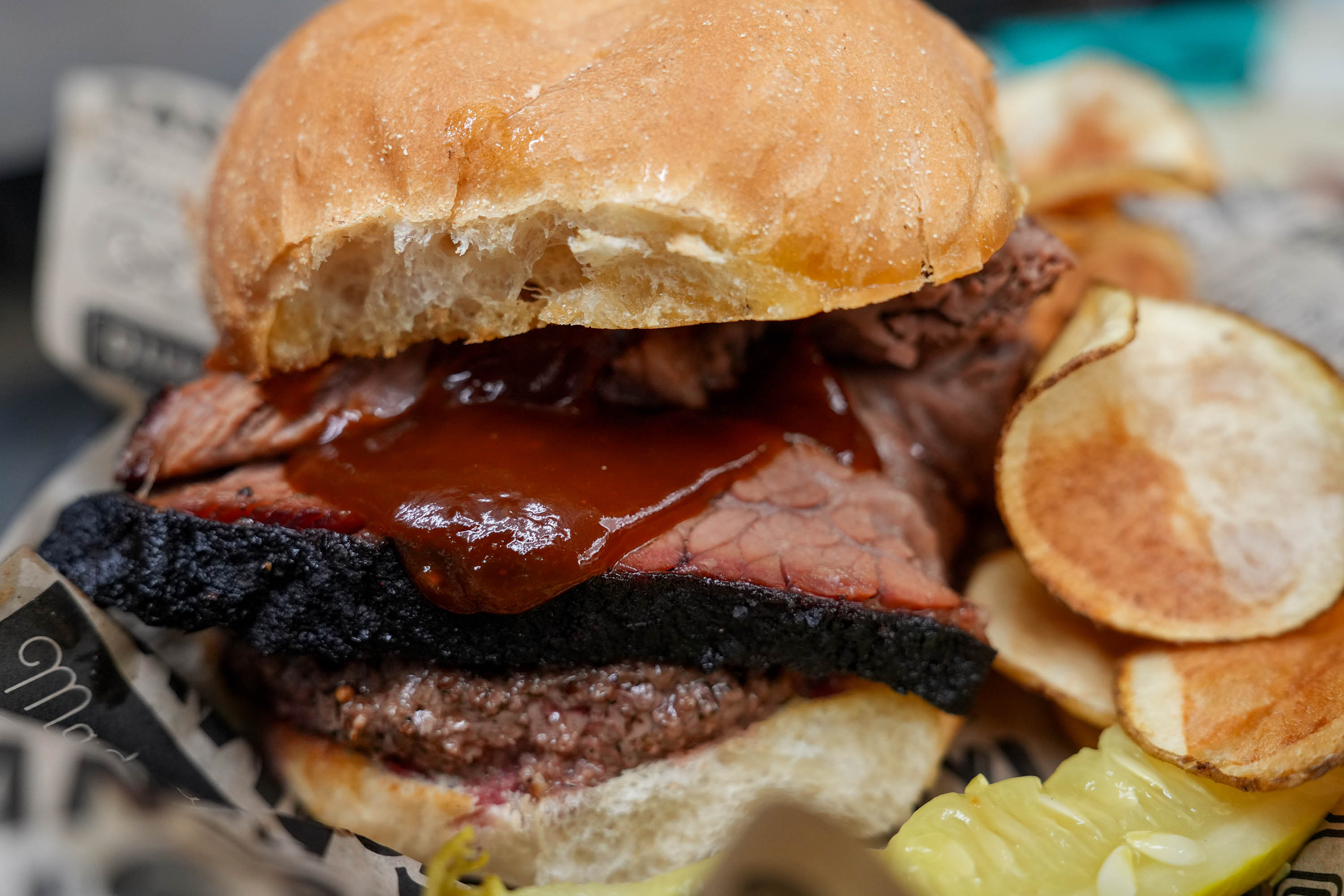 Smoked brisket burger topped with barbecue sauce and served with chips